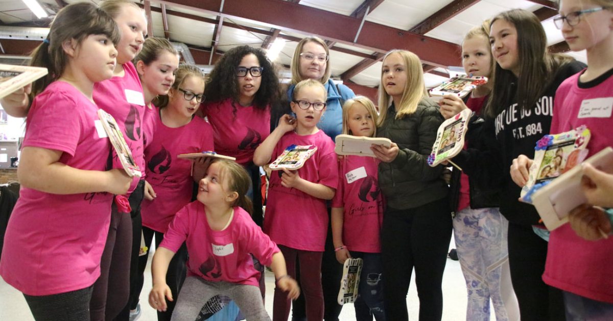 Group of tween girls holding colorful decorated photo frames during a creative confidence conference at Girls on Fire event