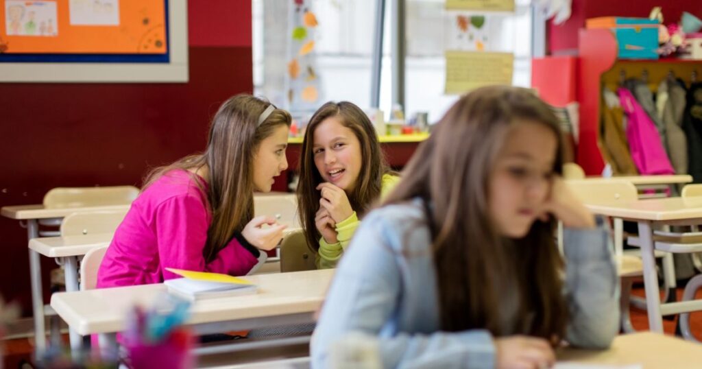 Tween girl feeling isolated in classroom while peers whisper, highlighting the importance of body image, confidence, and empowerment programs in Alberta