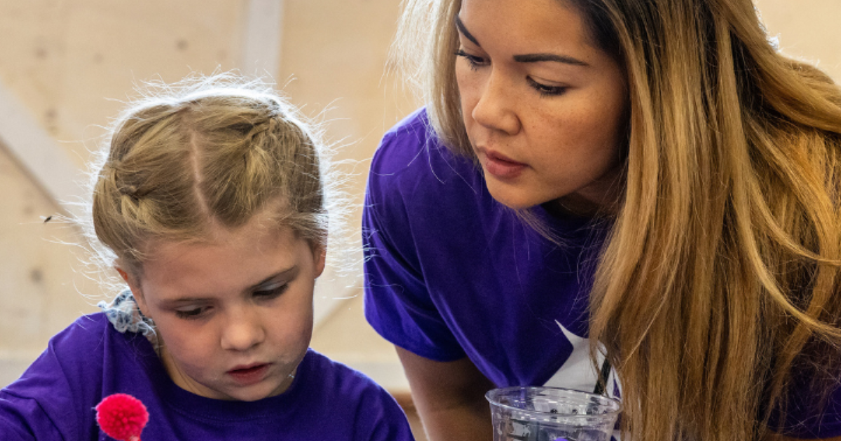 Adult mentor and founder supporting a young girl during a hands-on activity at a Girls On Fire empowerment program in Alberta.