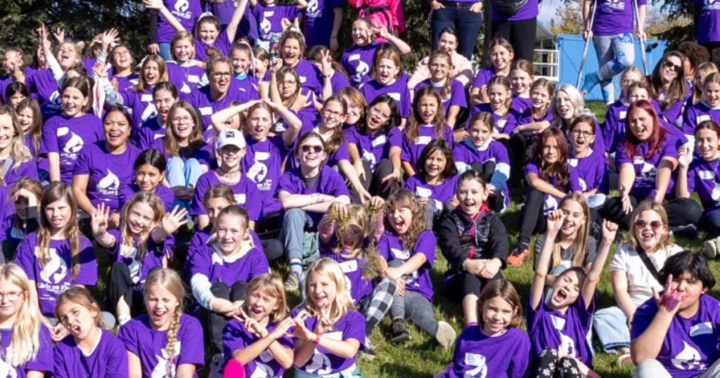 A large group of Alberta girls celebrating together at a Girls on Fire empowerment event parents have chosen that is focused on confidence building, community, and leadership.