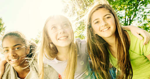 Three tween girls smiling together during a confidence building programs and experience in Alberta